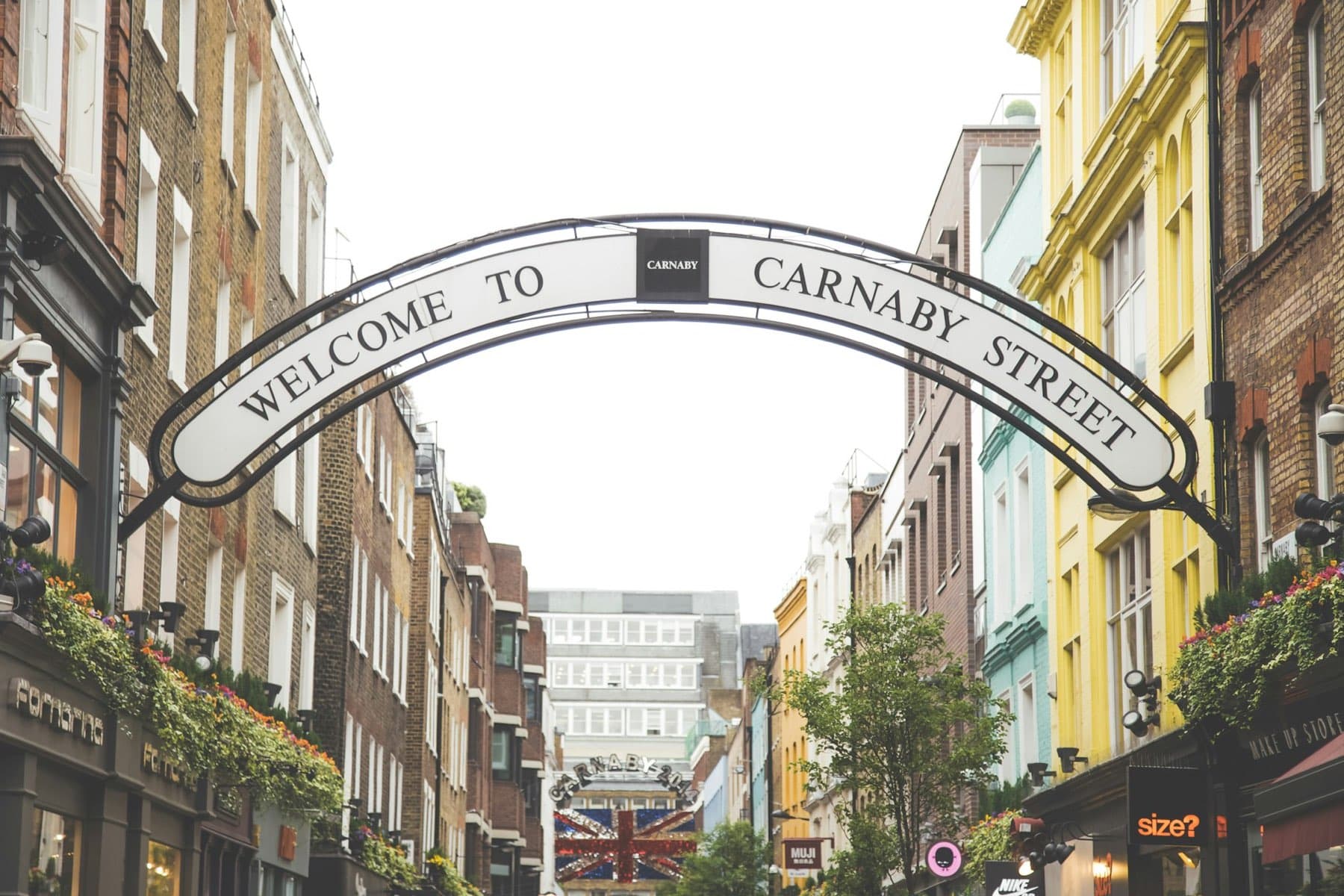 The Welcome to Carnaby Street arch spanning the pedestrianised street, painted shopfronts either side.